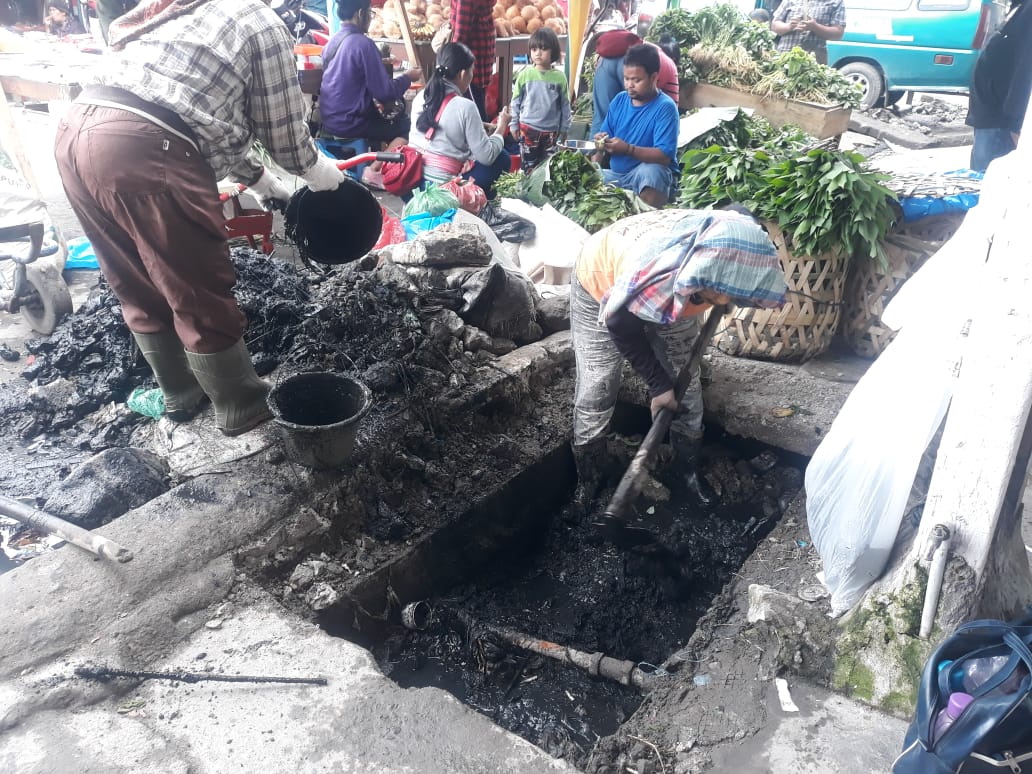 Petugas Dinas PUPR Kabupaten Karo saat memperbaiki drainase di Jalan Perniagaan Berastagi