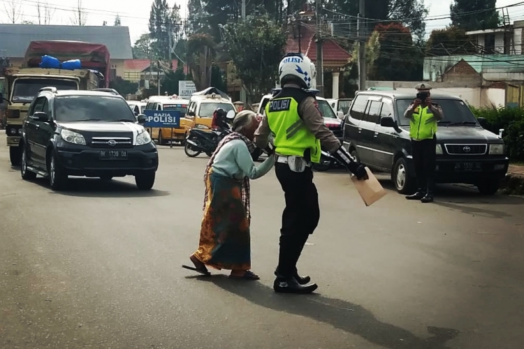 Polisi sedang menyeberangkan seorang nenek tua saat melakukan razia rutin di seputaran tugu bambu runcing Kabanjahe