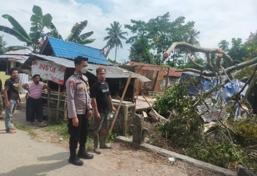 Bhabinkamtibmas Polsek Medang Deras bergotong royong bersama warga membersihkan kayu pohon yang tumbang (foto : HumaspolresBB)